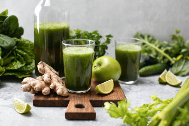 green detox smoothies with fresh leafy vegetables and ginger, front view